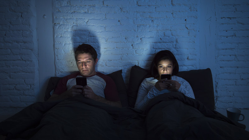 Couple in Bed Using Mobile Phones