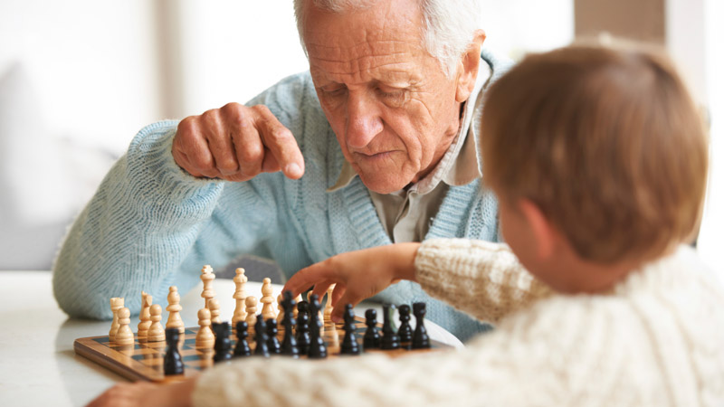 Sharp Elderly Man Teaches Child Chess